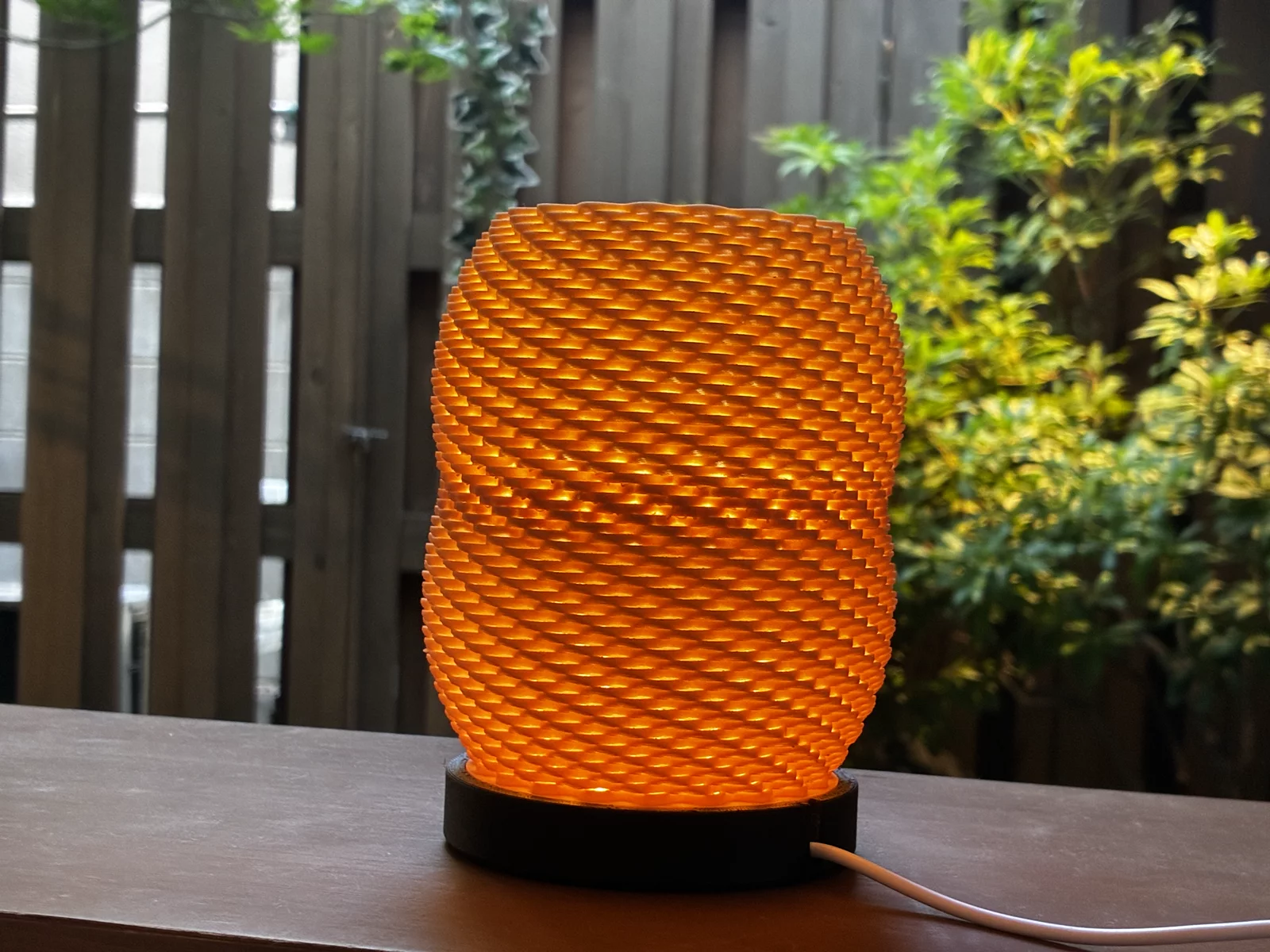 NITE Weave amber lamp lit on a ryokan veranda, wooden fence and garden behind
